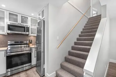 a staircase in a kitchen with a stainless steel refrigerator at 2BR in Snowberry, Wood Burning Fireplace, Modern Finishes, Parking, Ski Hill Shuttle in Whistler