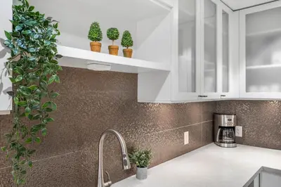 a kitchen with white cabinets and potted plants at 2BR in Snowberry, Wood Burning Fireplace, Modern Finishes, Parking, Ski Hill Shuttle in Whistler