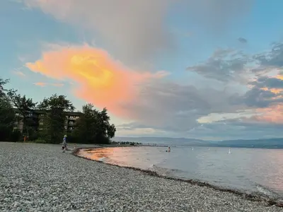 a person walking on a beach near the water at 1 bedroom lake Mountain view in West Kelowna