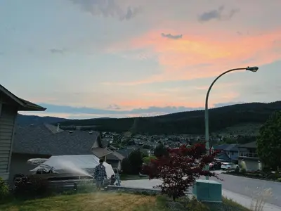 a man standing on a hill with a water hose at 1 bedroom lake Mountain view in West Kelowna
