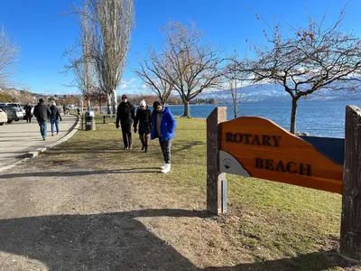 a group of people walking down a sidewalk next to a sign at 1 bedroom lake Mountain view in West Kelowna