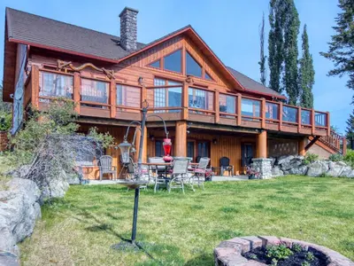a log home with a table and chairs in the yard at Pine Ridge, Log Home with Lake View and Backyard in Invermere