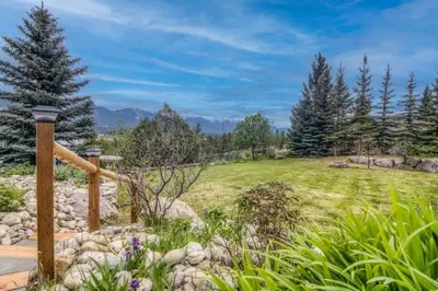a garden with a stone path and trees and mountains at Pine Ridge, Log Home with Lake View and Backyard in Invermere