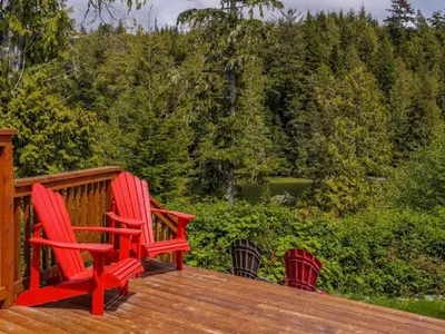 two red chairs sitting on top of a wooden deck at Bear Coast, Cabin with Hot Tub, Patio, and Waterview in Ucluelet
