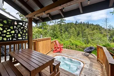 a deck with a picnic table and a hot tub at Bear Coast, Cabin with Hot Tub, Patio, and Waterview in Ucluelet