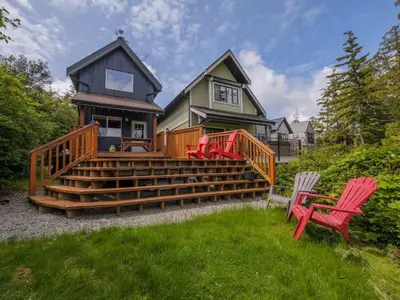 a house with two red chairs sitting on the steps at Bear Coast, Cabin with Hot Tub, Patio, and Waterview in Ucluelet