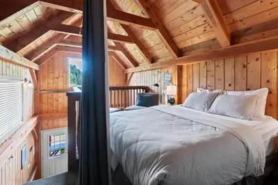 a bedroom with a bed in a wooden cabin at Bear Coast, Cabin with Hot Tub, Patio, and Waterview in Ucluelet