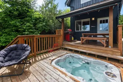 a hot tub on the deck of a house at Bear Coast, Cabin with Hot Tub, Patio, and Waterview in Ucluelet