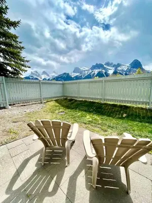 two chairs sitting on a patio with mountains in the background at Nakiska, 2 Bed 1 Bath with Mtn Views in Canmore