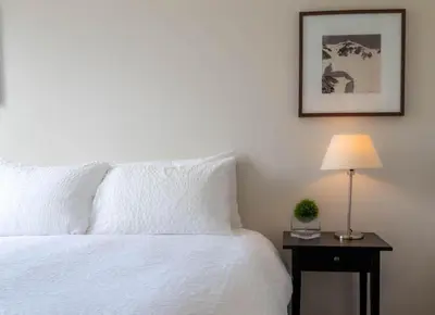 a bedroom with a white bed and a table with a lamp at Alpenglow Lodge Fika One Bedroom by MVA in Whistler