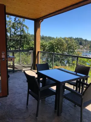 a table and chairs on a patio with a view at Mariner's Loft - Salt Spring Island in Ganges