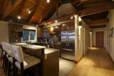 a kitchen with a stainless steel refrigerator and wooden cabinets at Mariner's Loft - Salt Spring Island in Ganges