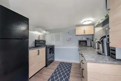 a kitchen with a black refrigerator and wooden cabinets at Quaint 1 bedroom lower suite in Victoria, BC in Victoria