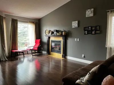 a living room with a fireplace and red chairs at citadle hill house! in Calgary