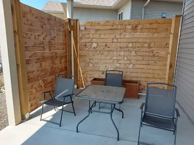 a patio with three chairs and a table and a fence at Peaceful and Spacious Lake View in West Kelowna