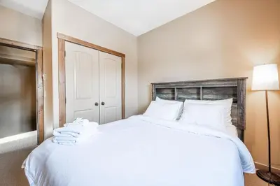 a bedroom with a large bed with white sheets at Trapper's Lodge - 4 Bd w Great View, Private Hot Tub in Big White