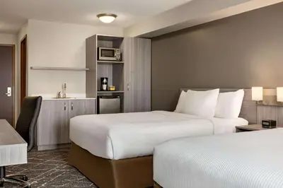 a hotel room with two beds and a kitchen at Microtel Inn & Suites by Wyndham Lloydminster in Lloydminster