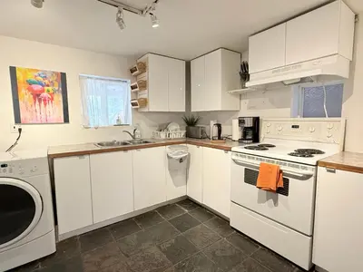 a kitchen with white cabinets and a washer and dryer at walk distance to kits beach 2bedrooms only for you in Vancouver