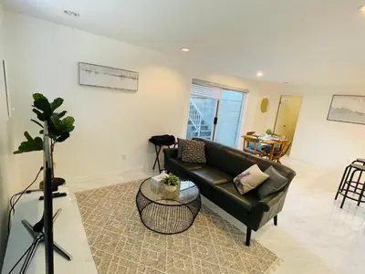 a living room with a black couch and a table at Adorable 2-Bedroom Basement in Vancouver in Vancouver