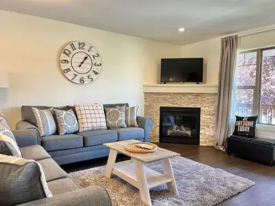 a living room with a couch and a clock on the wall at Perfect base Invermere 3bd townhouse mt views with garage in Invermere