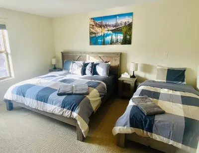 a bedroom with two beds and a painting on the wall at Perfect base Invermere 3bd townhouse mt views with garage in Invermere