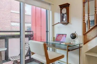 a desk with a chair and a clock next to a window at Victoria's Parliamentary Suite with Private Rooftop Patio & Harbour View in Victoria