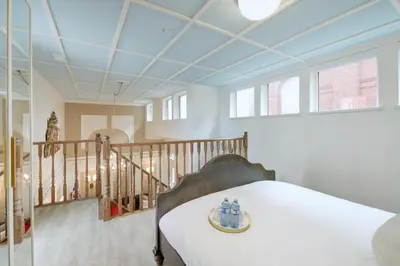 a room with a bed and a staircase with windows at Victoria's Parliamentary Suite with Private Rooftop Patio & Harbour View in Victoria