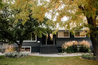 a black house with a tree in front of it at Waterfront Oasis with Pool, Hot Tub & Pet Friendly in Kelowna