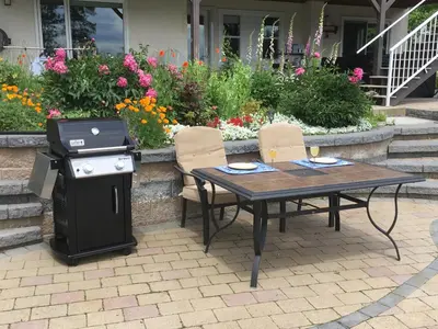 a table and chairs with a grill and flowers at Lakeview Gardens B&B in Peachland