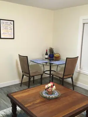a dining room table with chairs and a table with a bottle of wine at Lakeview Gardens B&B in Peachland
