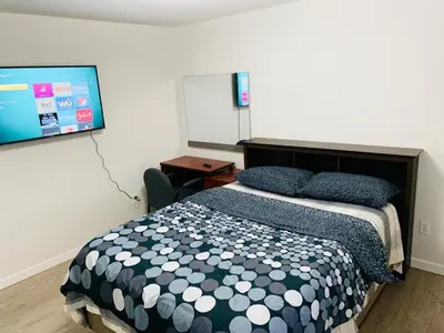 a bedroom with a bed and a flat screen tv at B&B In Fraser Valley in Abbotsford