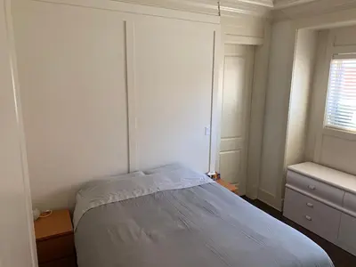 a white bedroom with a bed and a window at Private cozy suite near Dyke and Fisherman's Wharf in Richmond