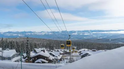 a ski lift with snow covered roofs and houses at Bear's Paw Chalet - Amazing Location & Ski In-Out in Big White
