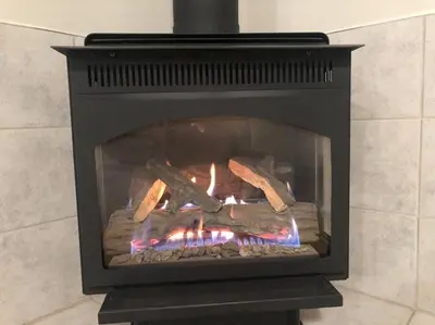a fireplace with logs and a fire in it at Licensed spacious basement suite with one king-size bed in Chilliwack