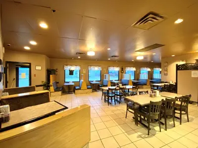 a restaurant with tables and chairs and a cafeteria at Beaverlodge Motor Inn in Beaverlodge