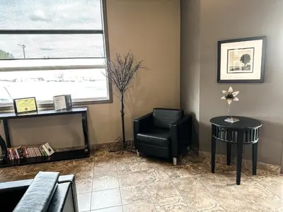 a living room with a black chair and a table at Beaverlodge Motor Inn in Beaverlodge