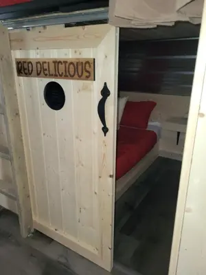 a bed in a tiny house with a cat on it at THE ORCHARD (HOSTEL WITH PRIVATE BUNKS) in Radium Hot Springs