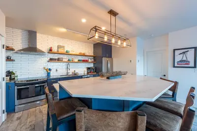 a kitchen with a large island with chairs in it at Fully Renovated Ski-in/out Loft with Private Hot Tub! in Golden