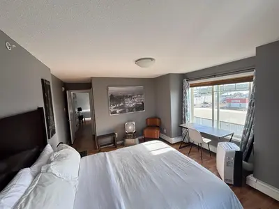 a bedroom with a bed and a desk and a window at Top Floor Riverfront Condo with Stellar Sunsets! in Fort McMurray