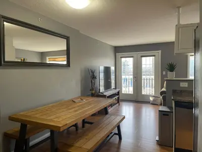 a living room with a wooden table and a mirror at Top Floor Riverfront Condo with Stellar Sunsets! in Fort McMurray