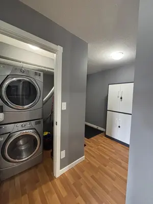 a laundry room with a washing machine and a washer at Top Floor Riverfront Condo with Stellar Sunsets! in Fort McMurray