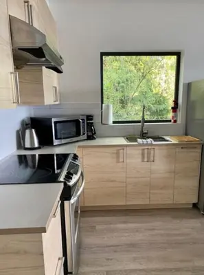 a kitchen with a sink and a microwave and a window at J and Js in Bowen Island