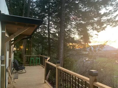 a wooden deck with a chair on a house at Tiny House Big View in Chilliwack