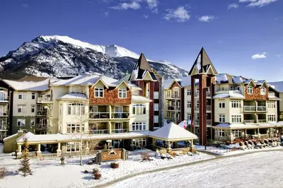 a resort in the snow with a mountain in the background at Romantic 1-Bedroom Serviced Apartment Kitchen & AC 143 in Canmore
