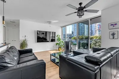 a living room with black leather furniture and a ceiling fan at Gastown Downtown Apartment very central in Vancouver