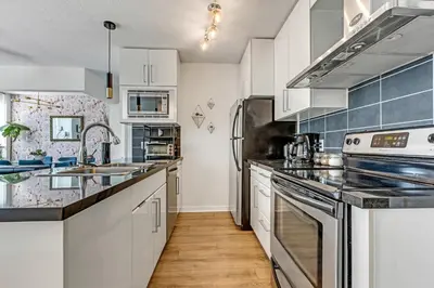 a kitchen with white cabinets and stainless steel appliances at Gastown Downtown Apartment very central in Vancouver
