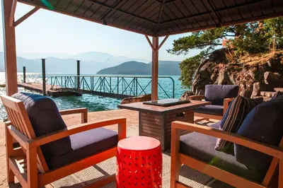 a patio with chairs and a table with a view of the water at The Overlook, Luxury Lakeside Home with Dock in Harrison Hot Springs