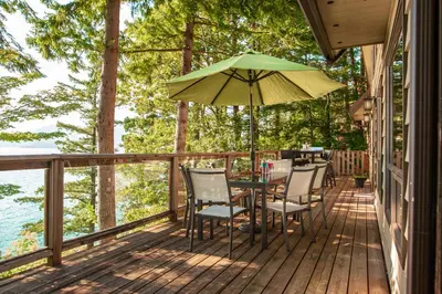 a patio with a table and chairs and an umbrella at The Overlook, Luxury Lakeside Home with Dock in Harrison Hot Springs