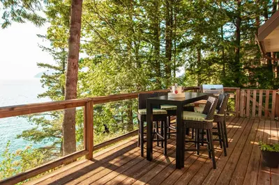 a table and chairs on a deck overlooking the water at The Overlook, Luxury Lakeside Home with Dock in Harrison Hot Springs