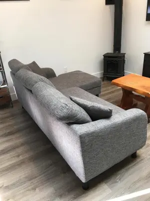 a gray couch sitting in a living room with a table at The Purple Door Carriage House in Lantzville
